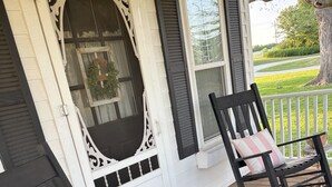 Une véranda avec deux fauteuils à bascule, chacun agrémenté d’un coussin à rayures.