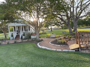 Surrounded by mature trees and landscaped gardens, this property offers a serene outdoor space with a wooden deck and covered porch.