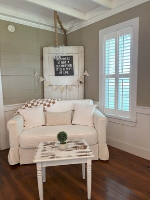 Relax in this inviting space with a comfortable sofa, a potted plant, and a decorative sign.