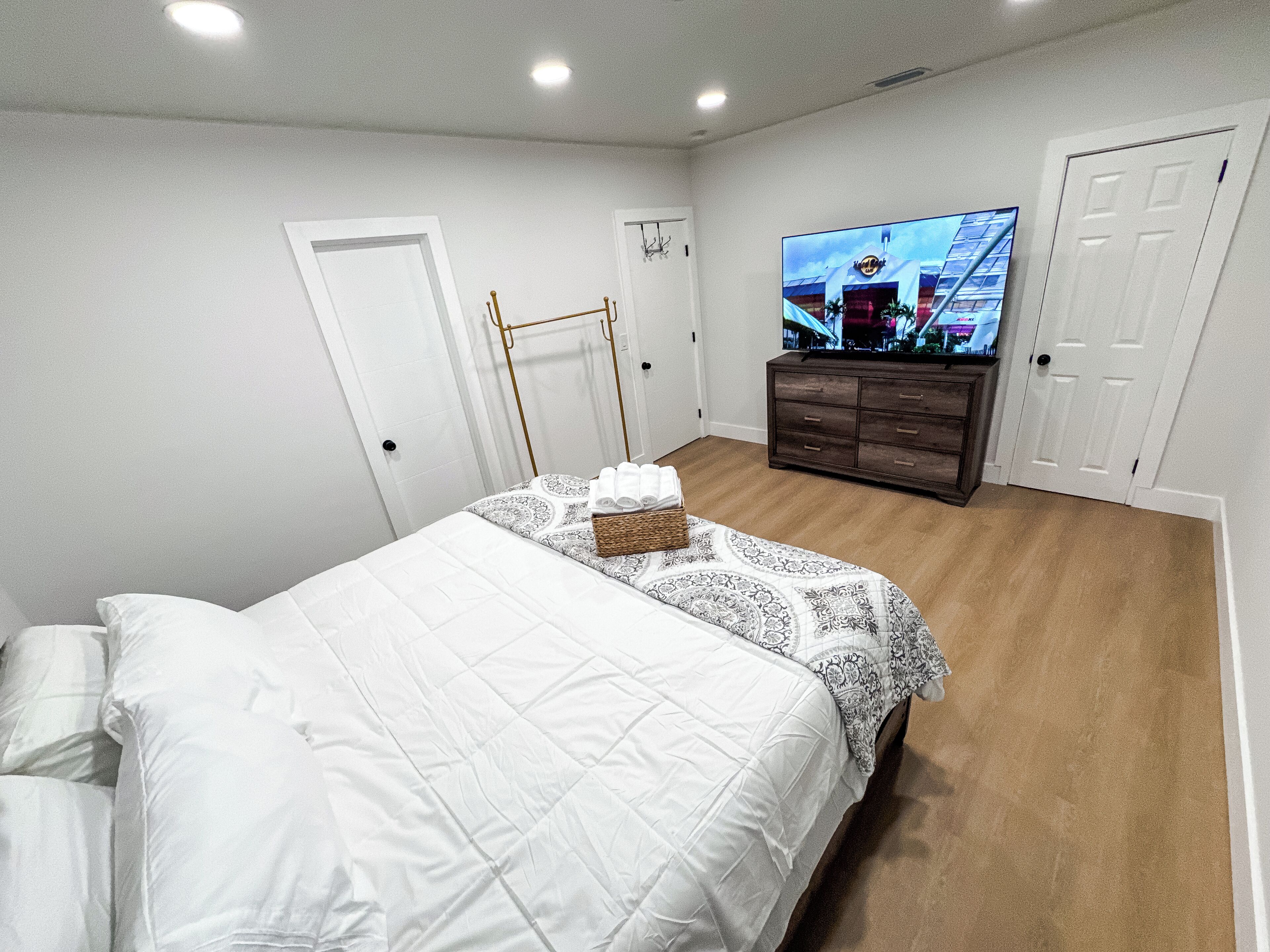 A bedroom with a bed, a television, a dresser, and a door.