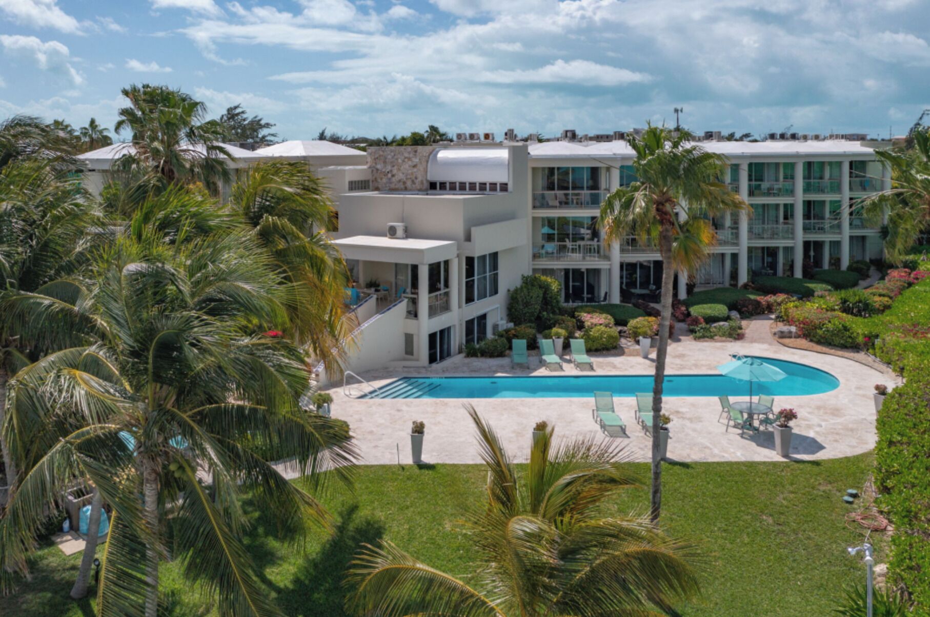 Ein modernes Hotel mit Pool, Palmen und einem gepflegten Garten.