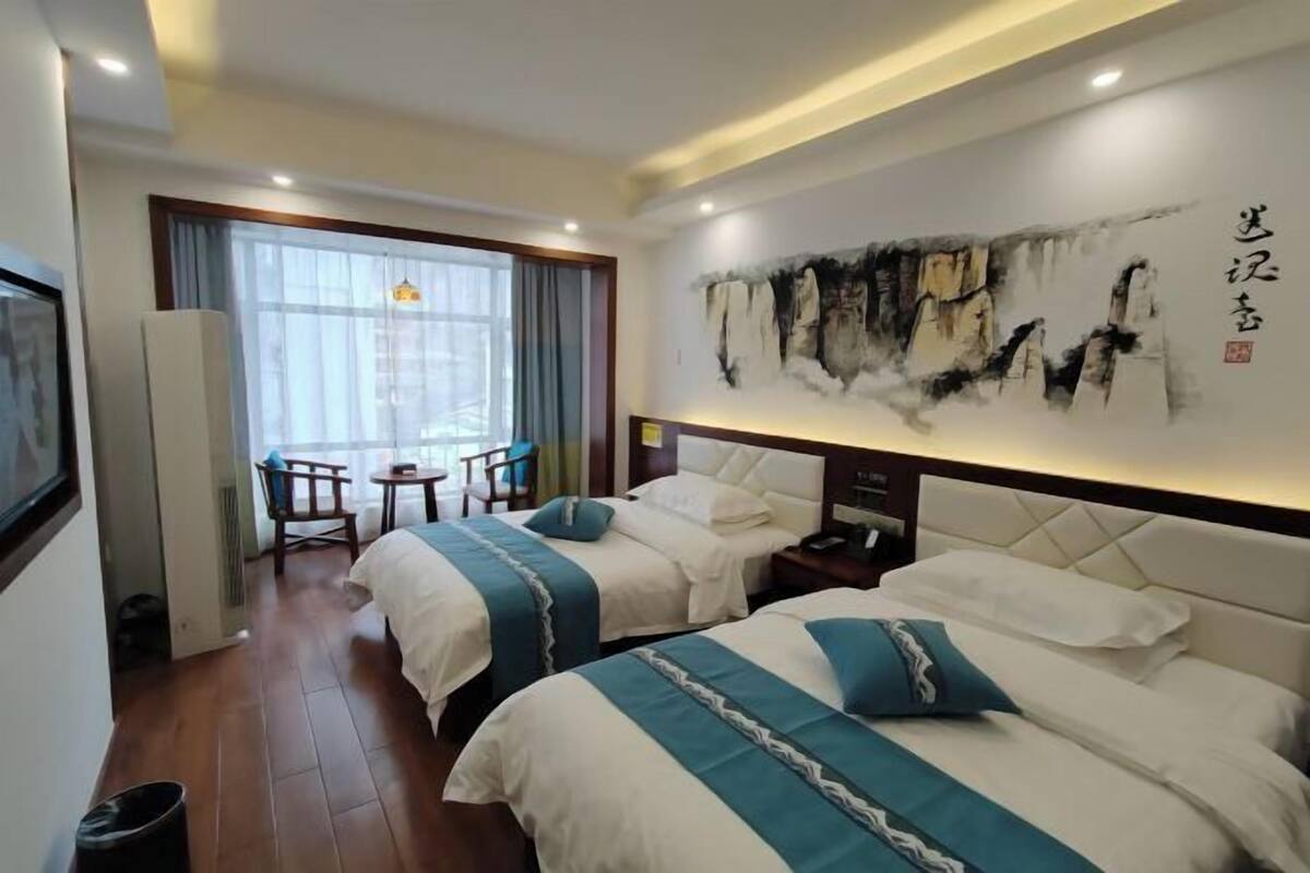Une chambre d’hôtel avec deux lits, un coin repas et un grand tableau au mur.