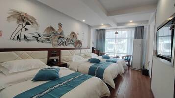 Quarto de hotel com três camas, um mural grande na parede e uma varanda com vista.