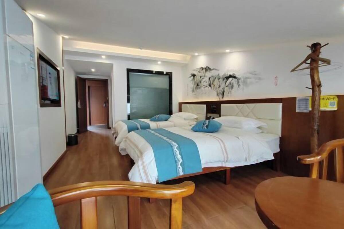 Une chambre d’hôtel avec un grand lit, une chaise en bois et une petite table.