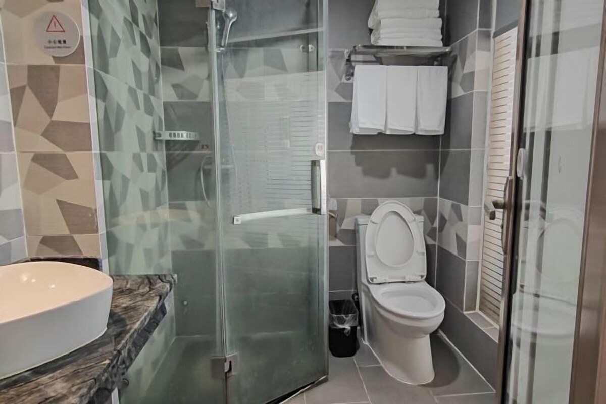 A bathroom with a glass-enclosed shower, a white sink, and a toilet.