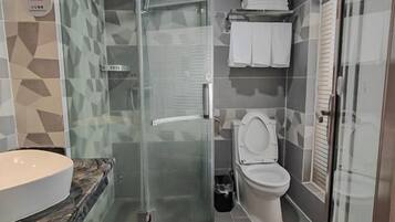 Un baño con cabina de ducha de vidrio, un lavabo blanco y un inodoro.