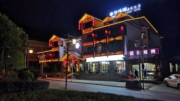 Een hotel met meerdere verdiepingen, een trap naar de ingang, en een bord dat een restaurant op de begane grond aangeeft.