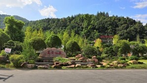 A landscaped area with a large rock, trees, and a mountain in the background. - Mengxiyuan Resort Hotel (Zhangjiajie)