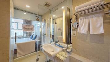 A modern bathroom with a glass shower enclosure, a sink, and a towel rack.