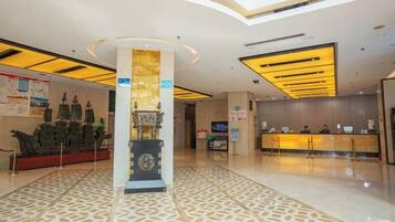 A hotel lobby with a reception desk, a decorative column, and a patterned floor.