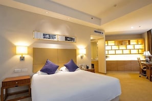 Habitación de hotel con una cama grande, lámparas de noche, un escritorio y un espejo.