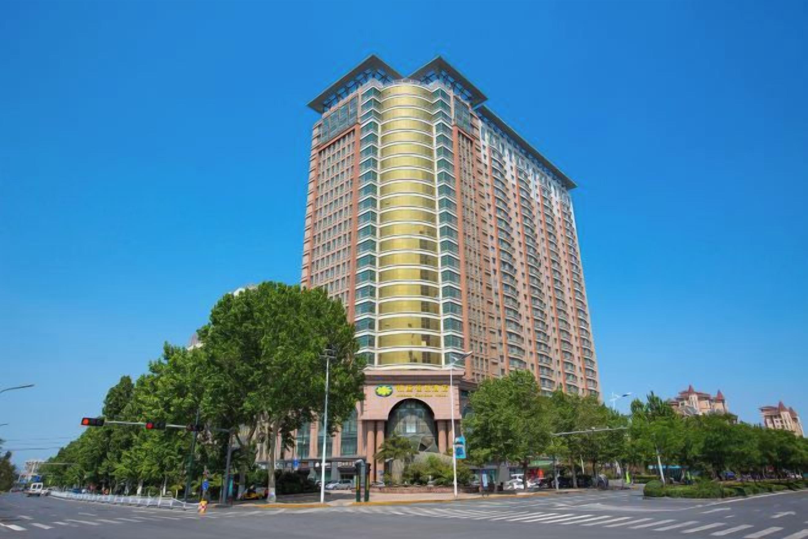 A tall hotel with a curved facade, multiple balconies, and a central entrance.