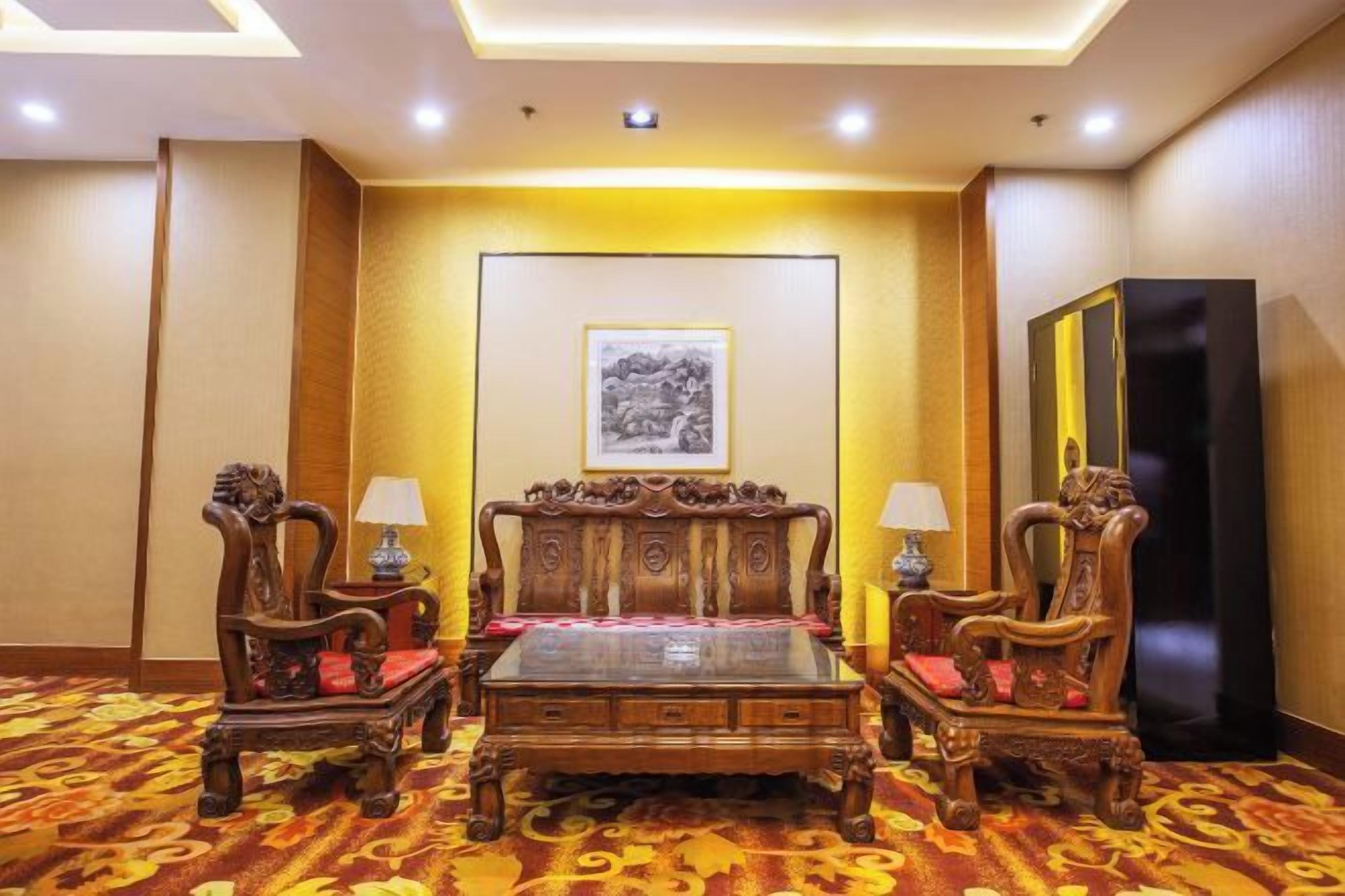 A hotel room with a large bed, two chairs, a table, and a mirror.
