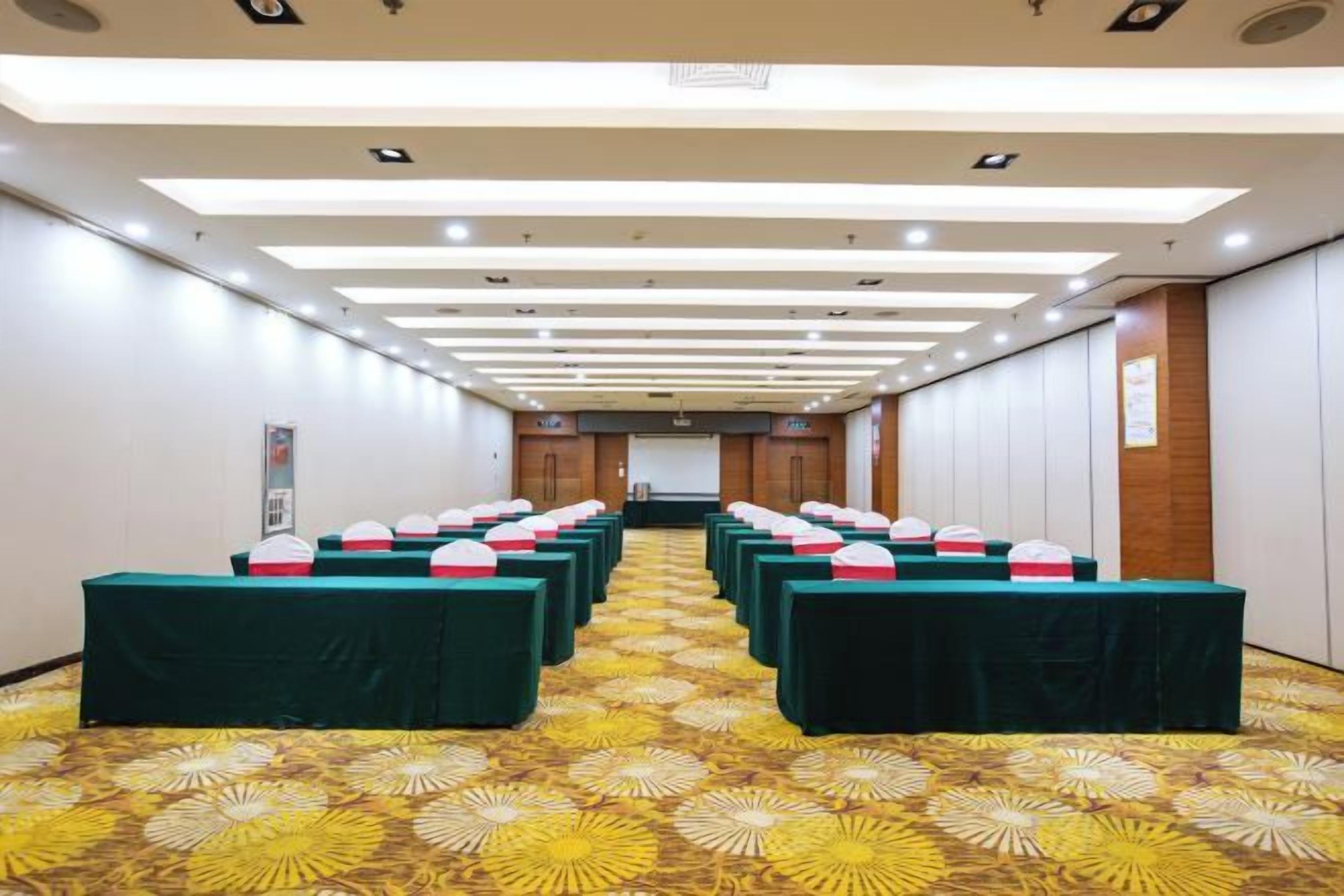 A conference room with rows of tables, chairs, and a patterned carpet.