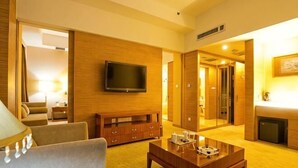 A hotel room with a TV, wooden furniture, a sofa, and a coffee table. - Jinan Zhangqiu Inzone Garland Hotel (Jinan)