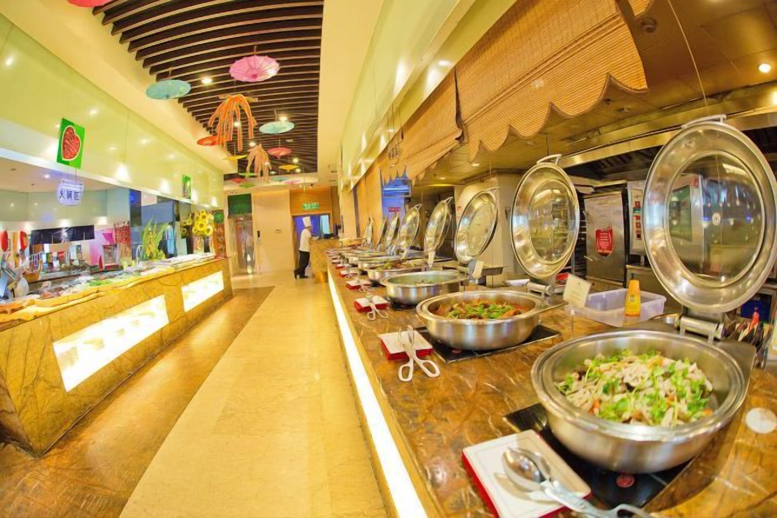 A buffet area with multiple food stations, a long counter, and a person in the background.