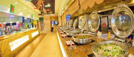 A buffet area with multiple food stations, a long counter, and a person in the background.