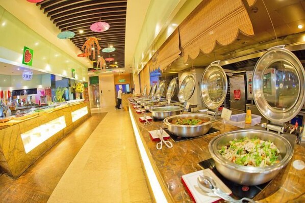 A buffet area with multiple food stations, a long counter, and a person in the background.