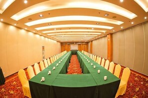 A conference room with a long table, chairs, and a carpeted floor.