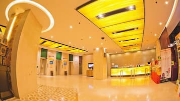 A hotel lobby with a reception desk, a large curved wall, and a patterned floor.