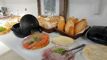 A buffet table with various food items, including bread, meat, and a cake.