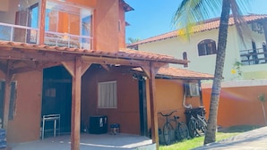 Un edificio de dos pisos con un balcón, una palmera y bicicletas estacionadas afuera.