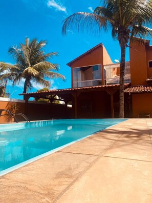 A swimming pool with a clear blue water surface, surrounded by a tiled deck. - Pousada Maresia Pier (Rio das Ostras)