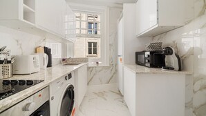 A compact kitchen with white cabinetry, a built-in washing machine, a microwave, and a toaster. - 3 Bedroom Apartment Steps from Piccadilly Circus! (London)