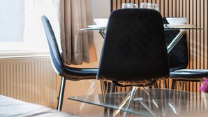 A dining area with a table and chairs, a window with curtains, and a wooden panel wall. - Stylish & Bright Studio in the Heart of Soho 8 (London)