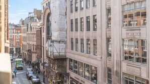 A street view of a city with historic buildings, a street lined with parked cars, and a building with a sign for 'HARMONIZED HOUSE'. - Stylish & Bright Studio in the Heart of Soho 8 (London)