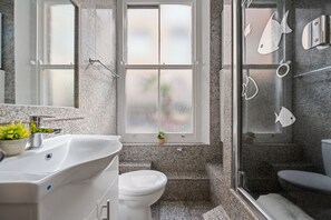 Ein Badezimmer mit einem großen Waschbecken, Toilette und einer Duschkabine aus Glas.