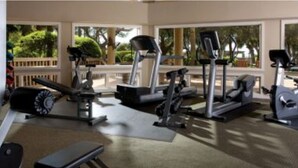 Ein Fitnessstudio mit Laufbändern, Crosstrainern und Gewichtsbänken.