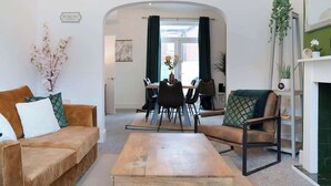 A modern living room with a sofa, armchair, coffee table, dining area, and a fireplace. - Central Darlington Sleeps 8 with WiFi and Parking (Darlington)