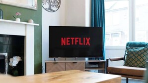 A living room with a television displaying 'NETFLIX,' a fireplace, a sofa, and a window with curtains. - Central Darlington Sleeps 8 with WiFi and Parking (Darlington)