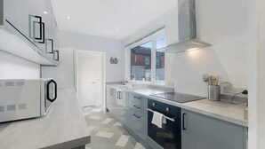 A modern kitchen with a built-in oven, a microwave, and a large window. - Central Darlington Sleeps 8 with WiFi and Parking (Darlington)