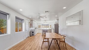 A modern kitchen with a wooden dining table, white cabinets, and a large window. - Private compound, offering three separate living spaces! multi families,groups (Desert Hot Springs)