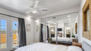 A modern hotel room with a large bed, a ceiling fan, a TV, and a sliding glass door leading to a balcony. - Private compound, offering three separate living spaces! multi families,groups (Desert Hot Springs)