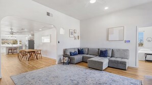A spacious living area with a grey sectional sofa, a wooden dining table, and a large rug. - Private compound, offering three separate living spaces! multi families,groups (Desert Hot Springs)