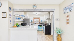 A modern kitchen with white cabinetry, a central island, and a decorative vase.