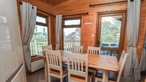 A wooden cabin with a dining table and chairs, large windows, and a balcony. - The Beach House (Ilfracombe)