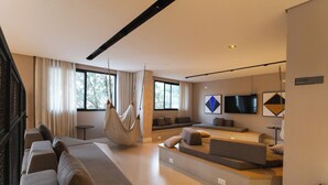 Ein modernes Wohnzimmer mit einem großen Sofa, einem Hängekorbsessel und einem flachbildfernseher an der Wand.