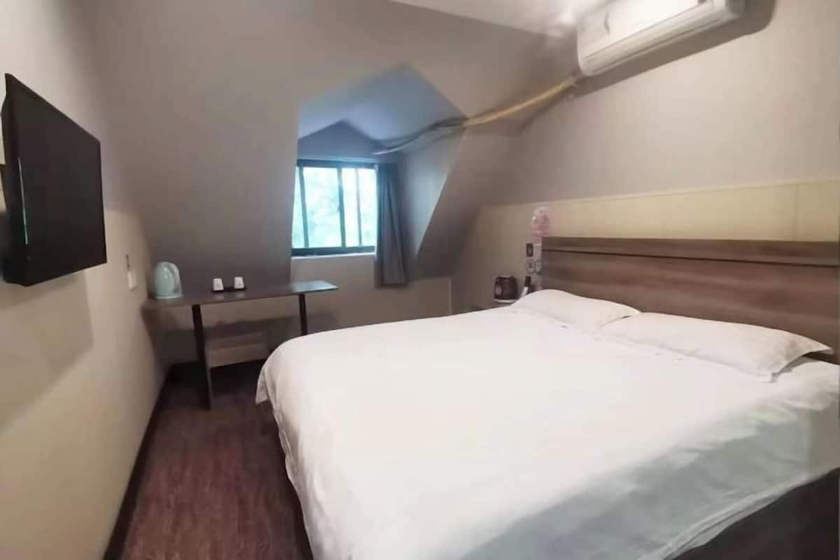 A hotel room with a bed, a desk, and a window.