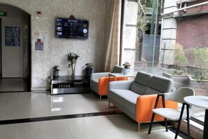 Rebedor d'hotel amb taulell de recepció, zona de seients i una finestra gran.