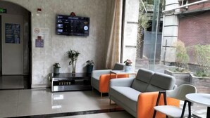 A modern lobby with a reception desk, seating area, and a large digital display.