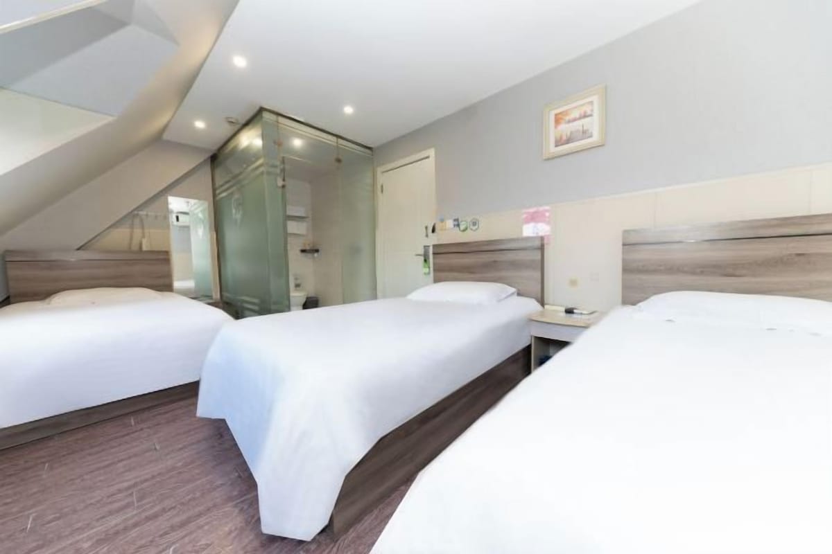Una camera d'albergo con tre letti, una scala e uno spazio doccia.