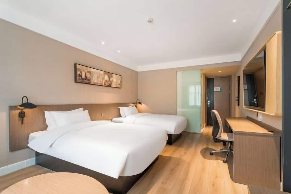 A hotel room with a large bed, a desk, and a chair.