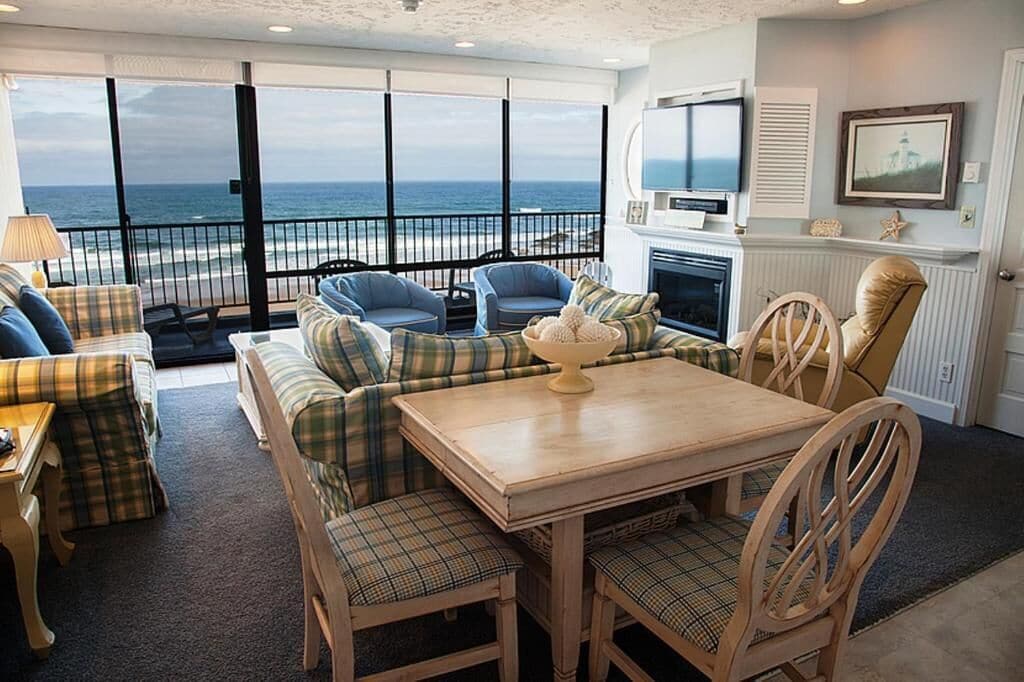 Una sala de estar con vista al océano, chimenea y televisor.