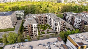 A modern apartment complex with multiple buildings, rooftop solar panels, and a central courtyard.