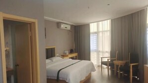 Une chambre d’hôtel avec un lit, un bureau, une chaise et une fenêtre avec des rideaux.