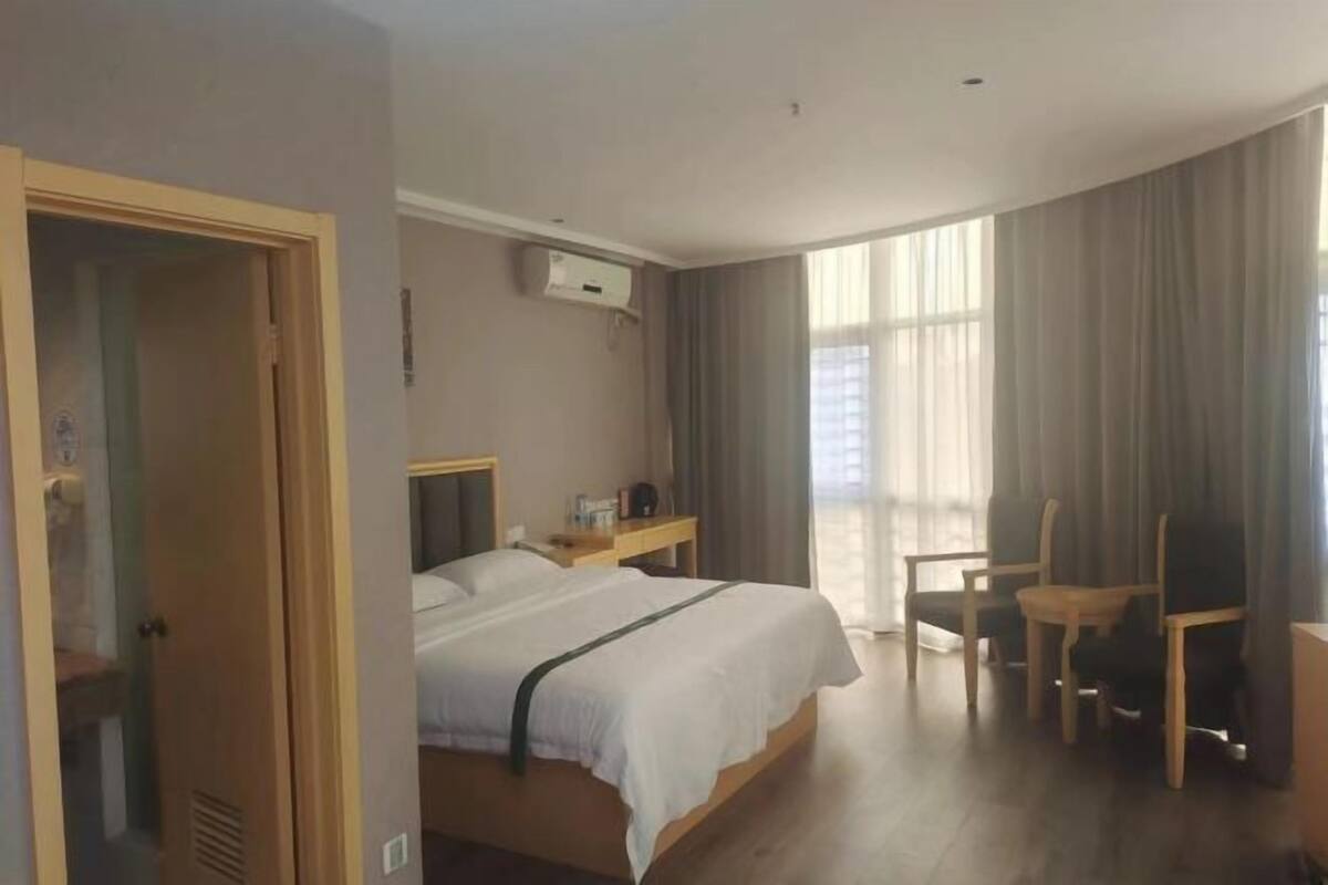 Una camera d'albergo con un letto, una scrivania, una sedia e una finestra con tende.